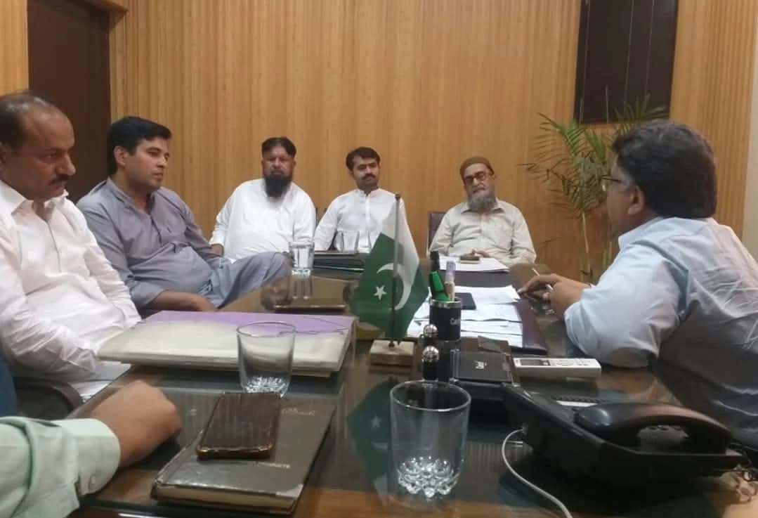 People in discussion around an office table with documents.